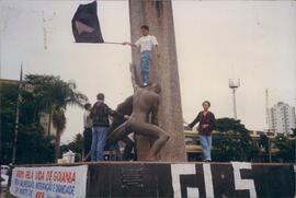 Manifestante hasteia bandeira no monumento às três raças  no centro de Goiânia